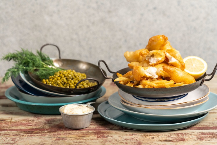 Fish and chips made with perch next to a bowl of green peas