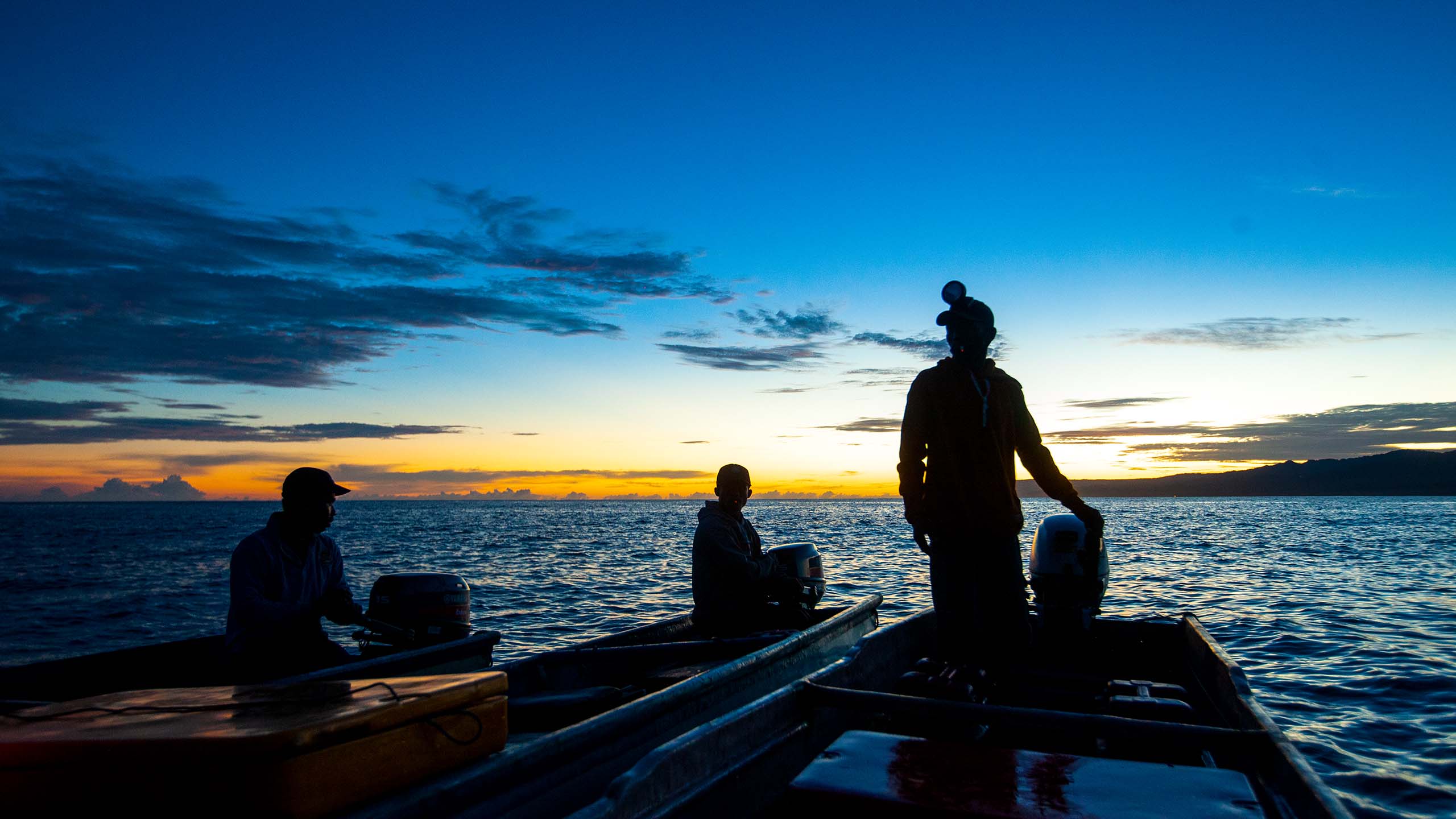 Two small tuna fishing boats next to each other at sunrise on choppy water