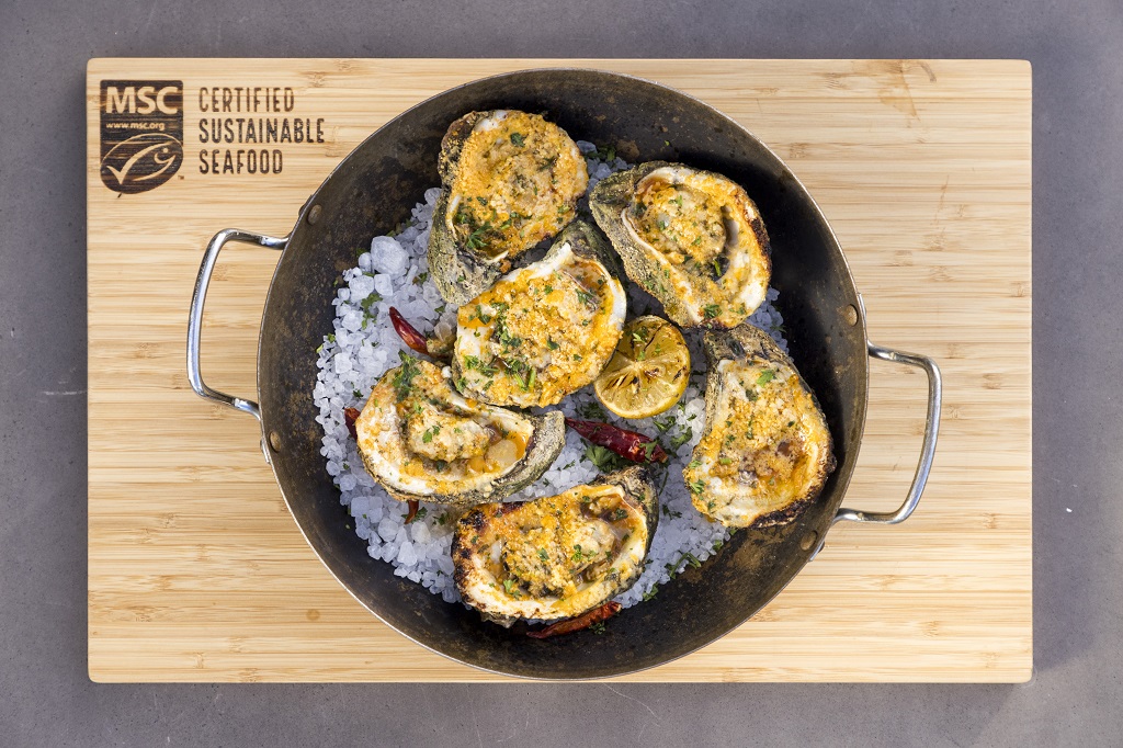 Photo of grilled oysters topped with garlic and parmesan cheese in a pan