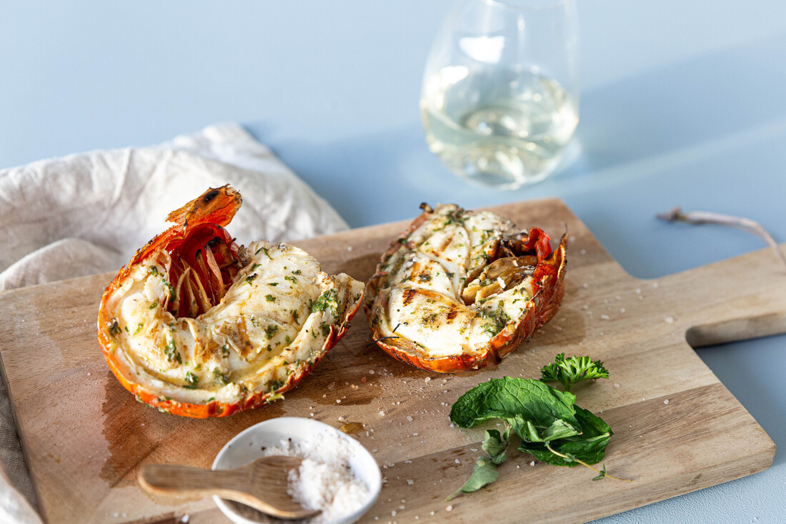 Grilled lobster tails on a wooden cutting board