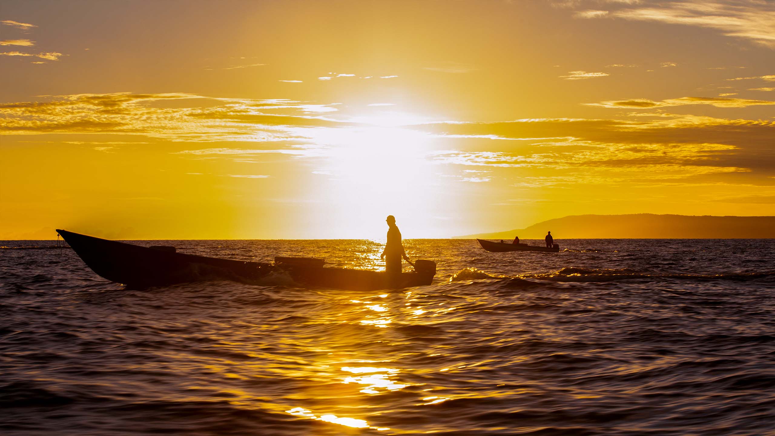 Two small tuna fishing boats heading out to sea at sunrise
