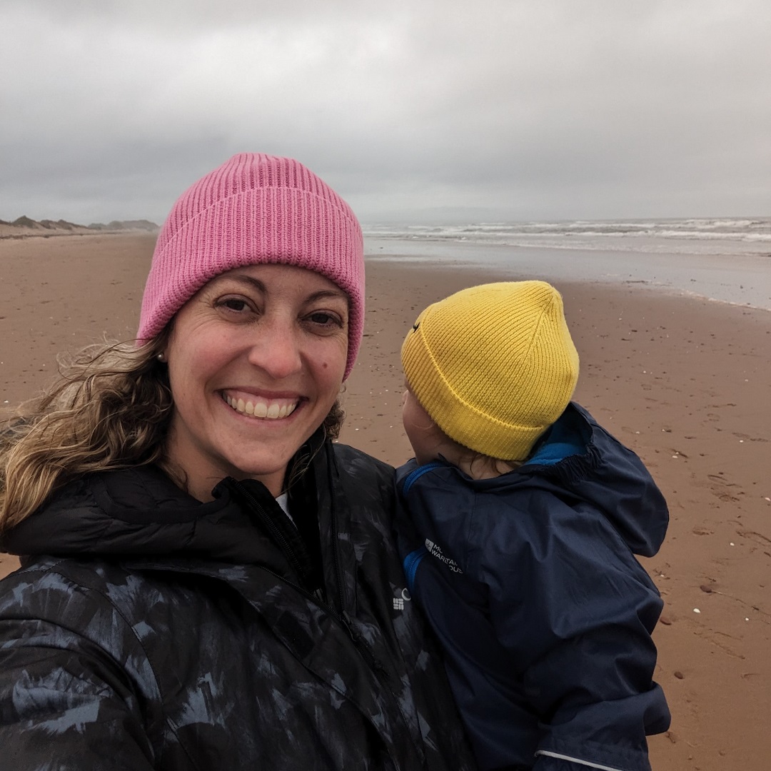 MSC staff member Cait Beatty holding her toddler on the beach on a gray day