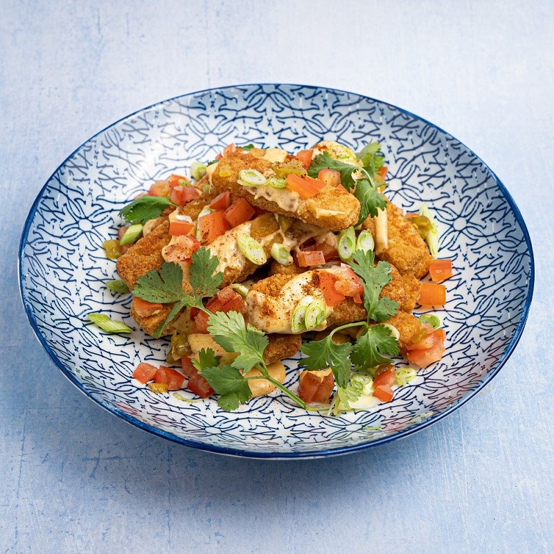 Fish fingers on top of nachos in a blue patterned bowl