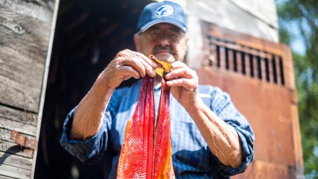 Man holding smoked salmon outside of smoke house