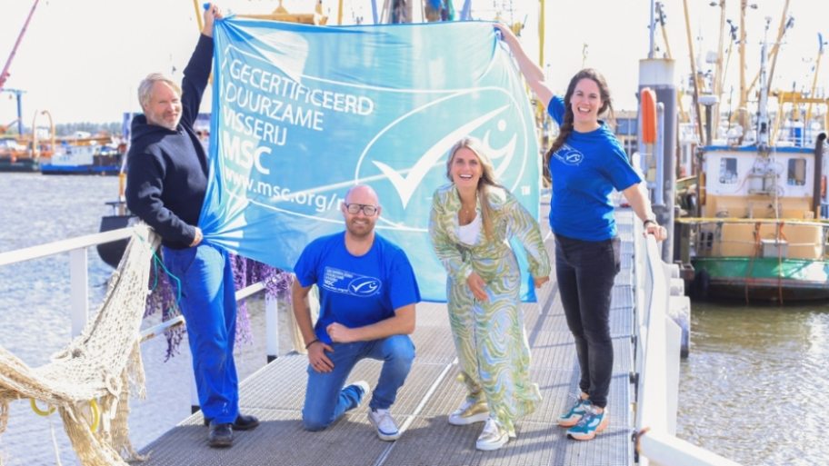 2 mannen en 2 vrouwen poseren voor een MSC-vlag