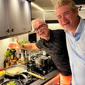 Två personer står i ett kök och lagar mat.