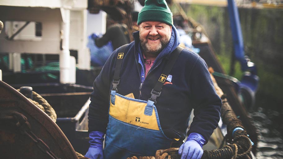 Fisherman in hat and protective clothing smiling at camera