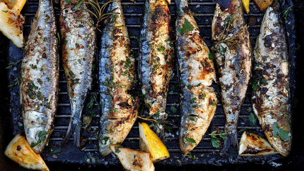 Grilled sardines on BBQ with lemon