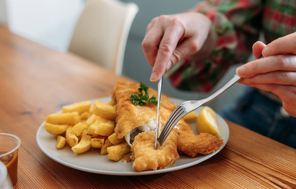 Women eating fish and chips off a plate at home