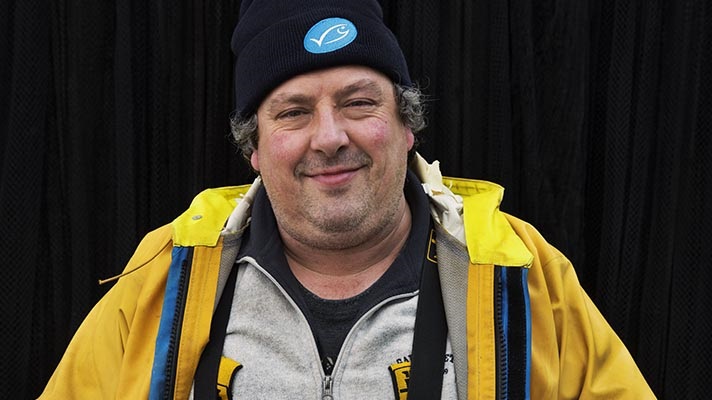 Headshot of man in woolen MSC logo hat and yellow waterproof coat