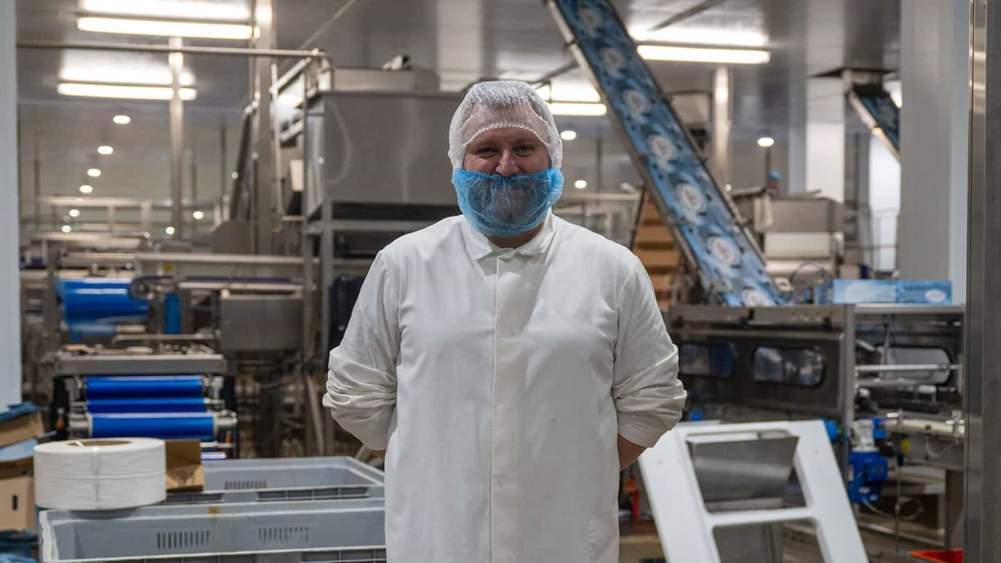 Herring factory worker standing in front of conveyer belt